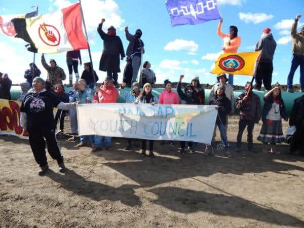 Youth Council holding their banner in front of the pipeline